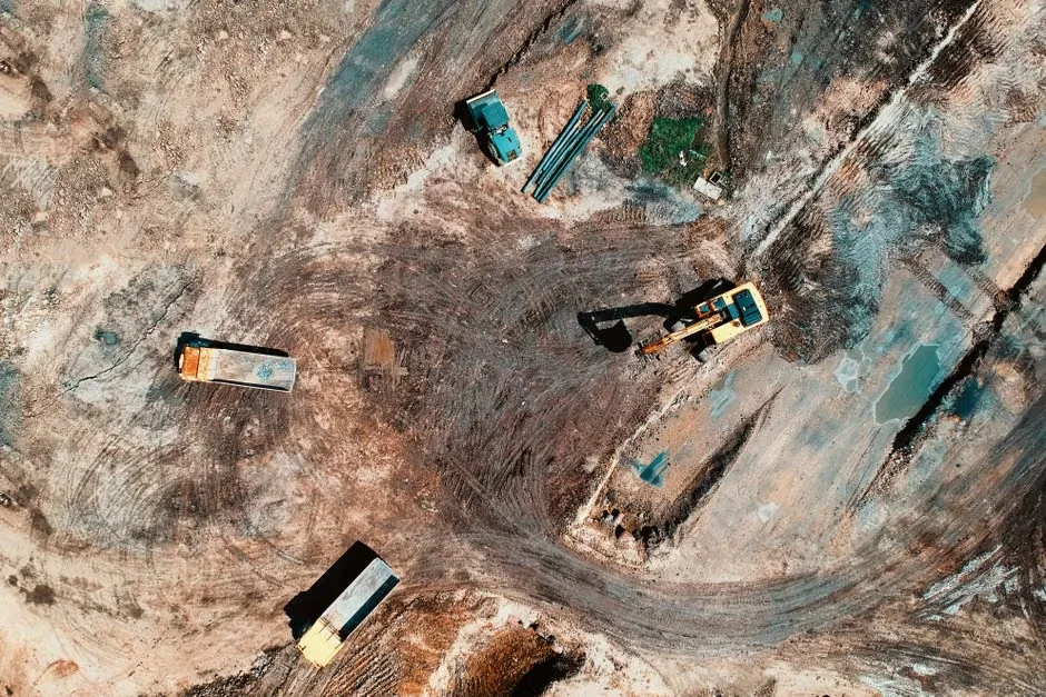 Aerial view of an excavator and dump trucks clearing and grading a Florida development site